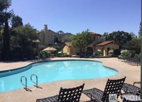 Newport Beach apartment for rent - A pool with chairs around it and a house in the background.