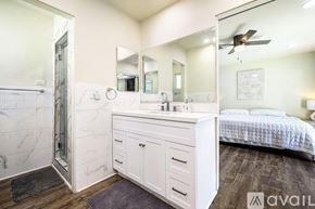 Palm Desert house for rent - A bedroom with a marble shower and a white vanity with a mirror above it.