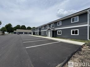 Nicollet apartment for rent - A parking lot in front of a grey building with trees in the background.