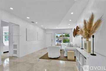 Miami house for rent - A modern living room with white furniture and a large window.