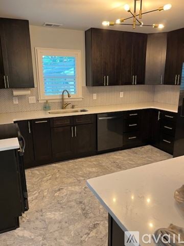 Smyrna house for rent - A kitchen with black cabinets and a marble countertop.