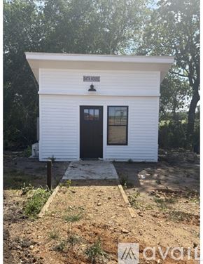 Fayetteville apartment for rent - A small white building with a black door and windows is in the foreground.