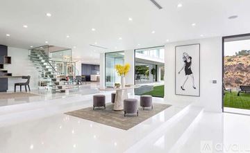 Los Angeles house for rent - A modern living room with a staircase and a painting of a tennis player.