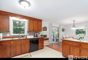 Merrimack apartment for rent - A kitchen with wooden cabinets and a black dishwasher.