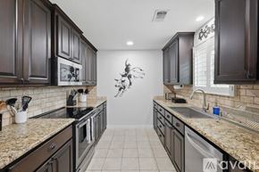 Keller house for rent - A kitchen with dark wood cabinets and granite countertops.