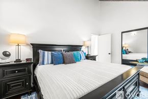 Imperial Beach condo for rent - A bedroom with a large bed, a nightstand with a lamp, and a mirror on the wall.