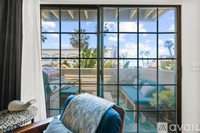 Imperial Beach condo for rent - A chair with a blue blanket is in front of a window with a view of a pool and palm trees.