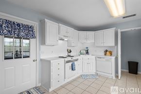 Sherwood house for rent - A kitchen with white cabinets and a window with a blue curtain.