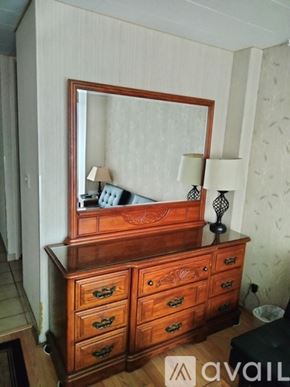 Honolulu condo for rent - A wooden dresser with a mirror on top and two lamps on either side.
