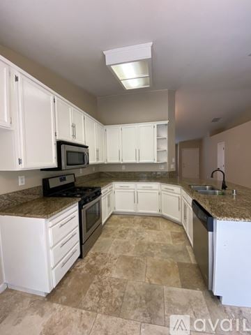 Roseville house for rent - A kitchen with white cabinets and a granite countertop.