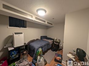Boston apartment for rent - A small, messy bedroom with a bed, desk, and clutter on the floor.
