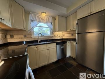 Norwood apartment for rent - A kitchen with a stainless steel refrigerator and a window with a view of trees.