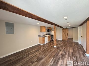 Bremerton apartment for rent - A room with wooden flooring and a kitchen area with wooden cabinets.