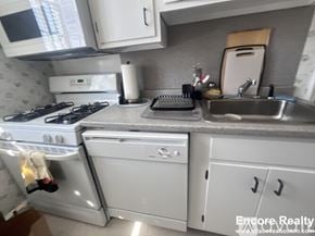 Brookline apartment for rent - A white stove and oven in a kitchen with a sink and microwave.