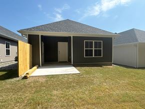 Little Rock house for rent - A small house with a grey roof and a brown door is surrounded by a grassy area.