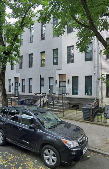Brooklyn apartment for rent - A black car is parked on the sidewalk in front of a white building.