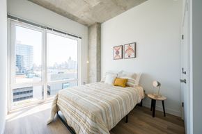 Chicago apartment for rent - A bedroom with a large bed and a view of the city.