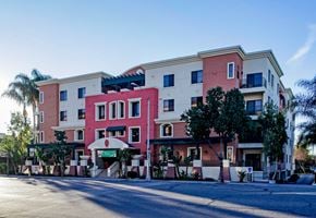 Fullerton apartment for rent - A multi-story building with a pink and beige facade.