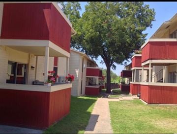 Dallas apartment for rent - A red and white building with a tree in front.