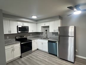 Dayton apartment for rent - A kitchen with a stainless steel refrigerator, black stove, and white cabinets.