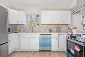 Englewood house for rent - A kitchen with white cabinets and a blue dishwasher.