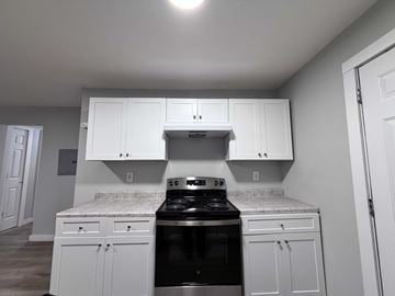 East Point apartment for rent - A kitchen with white cabinets and a black stove top oven.