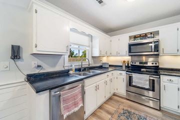 Hubert house for rent - A kitchen with white cabinets and a black countertop.