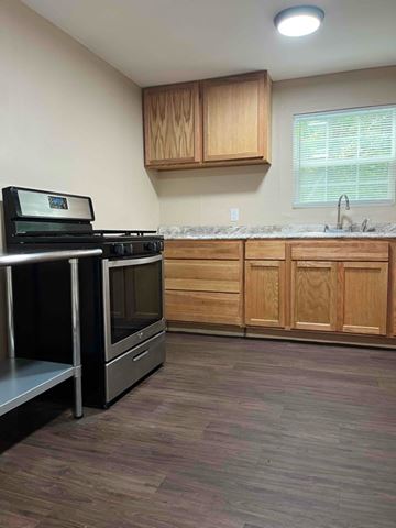 Nacogdoches apartment for rent - A kitchen with wooden cabinets and a black stove top oven.