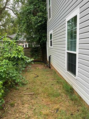Nacogdoches apartment for rent - A grey house with a window and a bush in front of it.