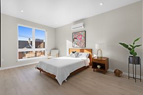 Newark apartment for rent - A bedroom with a large bed, a chair, a nightstand, and a plant.