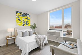 Newark apartment for rent - A bedroom with a bed, chair, and a painting on the wall.