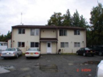 Kenai apartment for rent - A building with a white door and windows with cars parked in front.