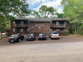 Nacogdoches apartment for rent - A parking lot with four cars and a building in the background.