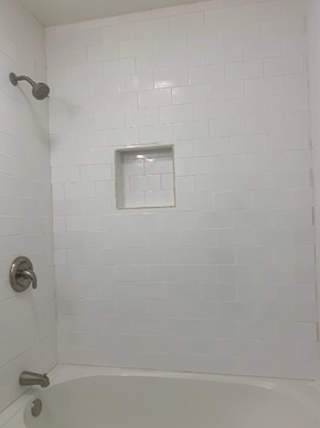 Nacogdoches apartment for rent - A white tiled shower with a glass door and a silver faucet.
