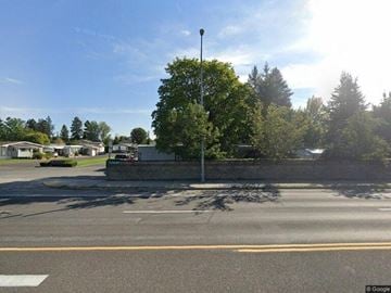 Post Falls house for rent - A street view with a tree in the middle of the road.