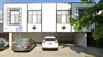Los Angeles apartment for rent - Two cars are parked in front of a white building with a sign that says "NOW SELLING".