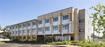 Ewa Beach apartment for rent - A modern building with a beige and white facade and a parking lot in front.