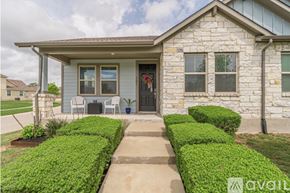 San Marcos condo for rent - A house with a grey exterior and a brown roof is surrounded by a grassy area and a curved driveway.