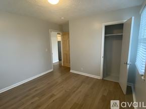 Nashville apartment for rent - A room with wooden floors and white walls, with a door on the right and a window with blinds on the far right.