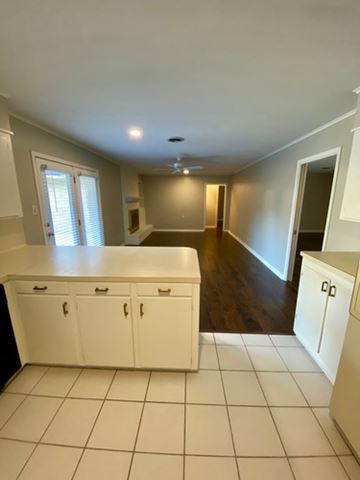 Shreveport house for rent - A kitchen with white cabinets and a tiled floor.