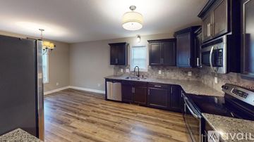 Clarksville house for rent - A kitchen with dark wood cabinets and a black refrigerator.