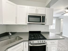 Chicago apartment for rent - A kitchen with white cabinets and a black microwave above the stove.