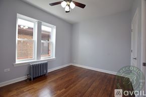 Chicago apartment for rent - A room with a ceiling fan and a window with a view of a brick building outside.