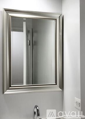 Chicago apartment for rent - A bathroom mirror with a silver frame is mounted on a white wall.