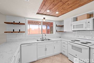 Vail house for rent - A kitchen with white cabinets and a wooden ceiling.