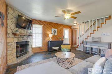 Granbury house for rent - A living room with a stone fireplace and a television above it.