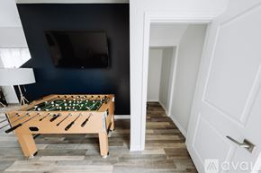 North Hollywood house for rent - A pool table with a green cloth and white balls is in the foreground of a room with a television and a white door.