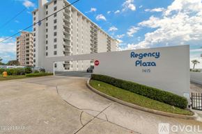 Ormond Beach apartment for rent - A white building with a sign that says "Regency Plaza 1415" in front of it.