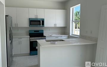 Miami-Dade County townhouse for rent - A kitchen with white cabinets and a blue oven.