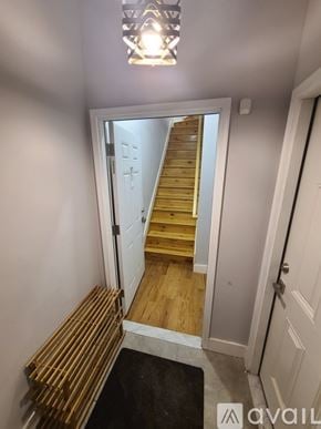 Brooklyn apartment for rent - A hallway with a wooden staircase and a white door.